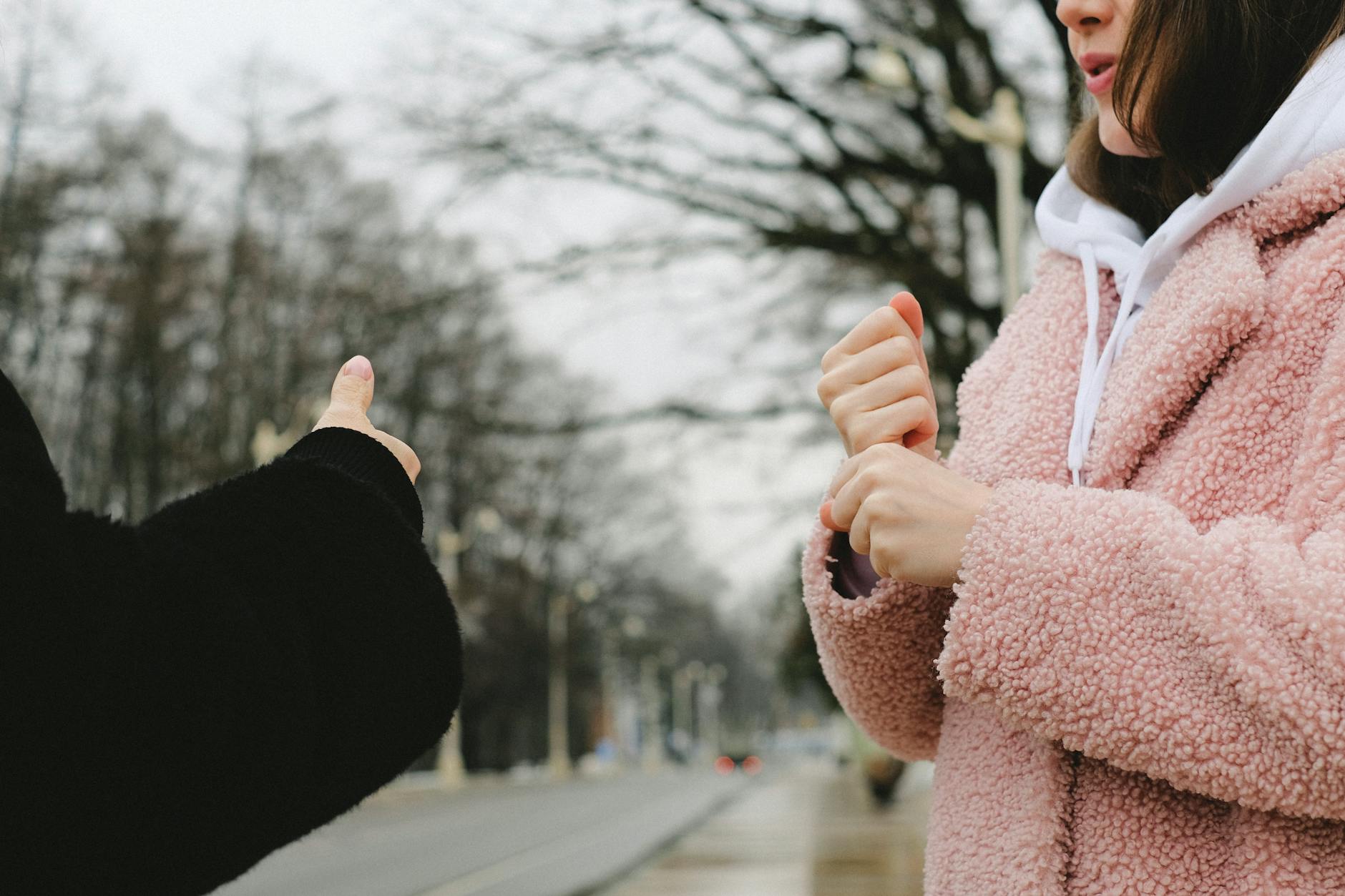 crop deaf friends chatting on street in winter